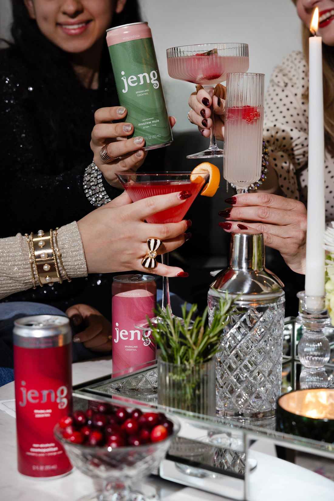 Group of friends toasting Jeng THC cocktails at a candlelit bachelorette party table with cocktail shaker and fresh herbs.