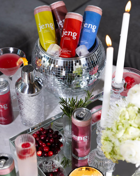 Jeng THC-free sparkling cocktails chilling in a disco ball cooler with candles, cranberries, and festive glassware on display.