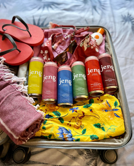 Assorted Jeng zero-proof THC cocktails packed in a travel suitcase ready for adventure.