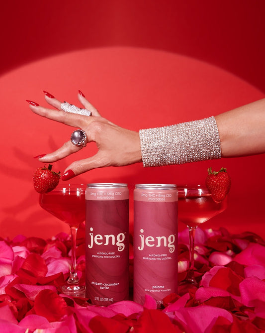 Two cans of Jeng Sparkling THC Cocktail—Rhubarb Cucumber Spritz and Paloma—next to champagne glasses on a Halloween-inspired table.