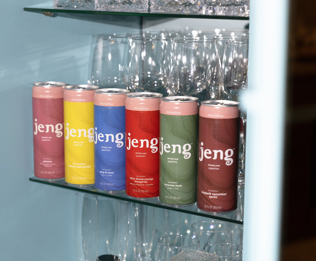 Jeng sparkling cocktails in colorful cans on a bar shelf with crystal glasses and bar tools.