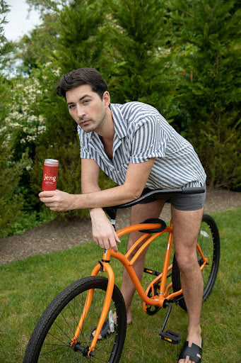 A cyclist sipping on a can of Jeng's non-alcoholic cocktail, representing a healthier lifestyle.