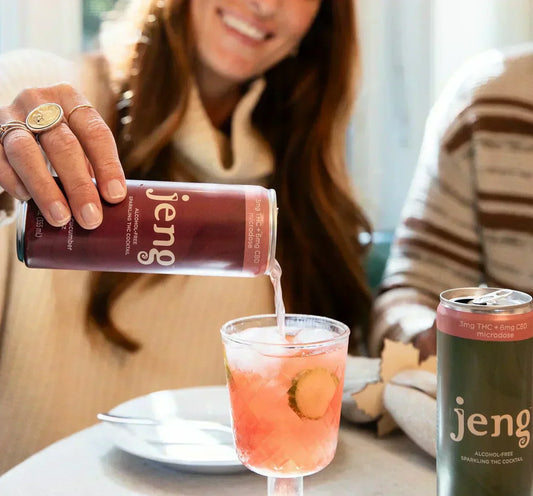 Friends celebrating indoors with Jeng sparkling THC cocktails, being poured into a glass with cucumber garnish.
